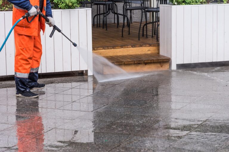 Worker cleans the sidewalk in front of a street cafe